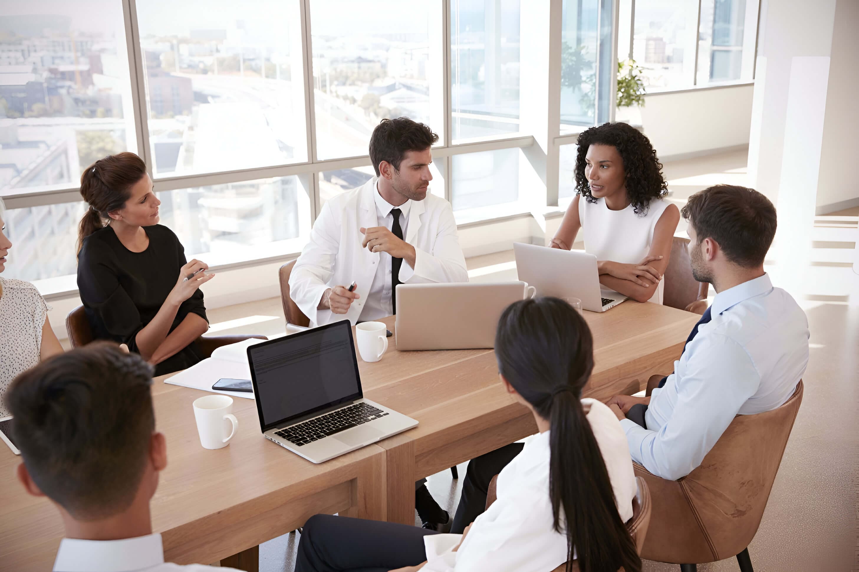 A group of people sitting around a table with laptops.