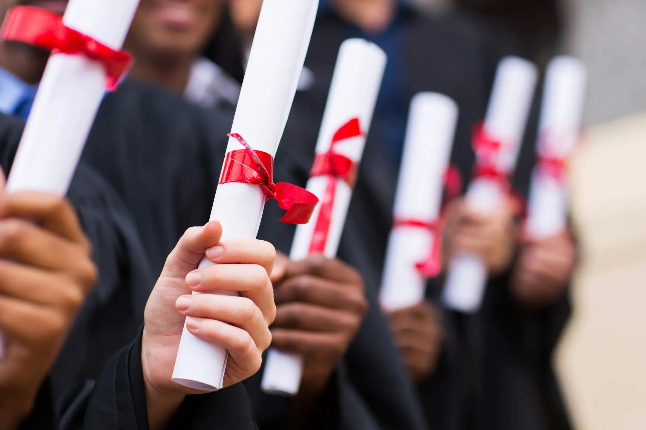 A group of people holding up their diplomas.